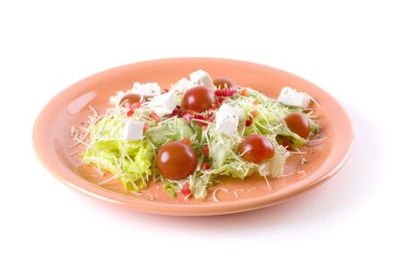 Fresh salad with feta and tomatoes on orange plateの写真素材