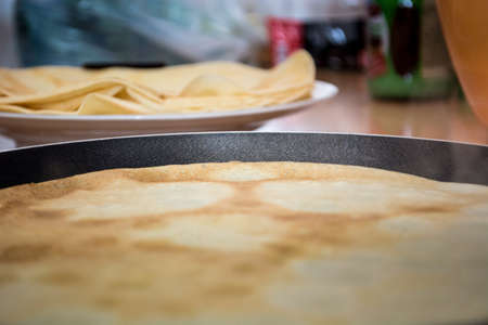 Baking pancakes with stack of pancakes in the backgroundの写真素材