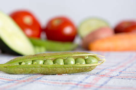 Green beans on a kitchen table with blurred background with other vegetables