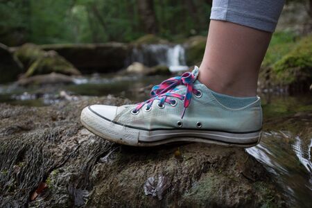 Girls foot stepping on a mossy rock. Blurry water stream in the backgroundの写真素材