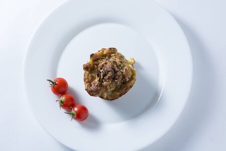 Ripe and red cherry tomatoes with zucchini muffins in white plate isolated on white backgroundの写真素材