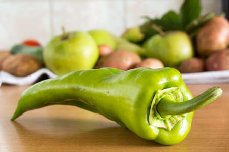 CLoseuo of the green pepper on the kitchen table with various vegetables in the backgroundの写真素材