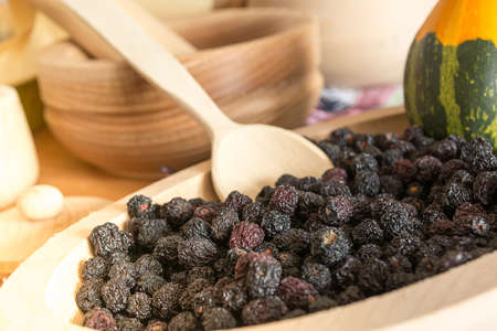 Chokeberry in small wooden plate with decorative pumpkin in itの写真素材