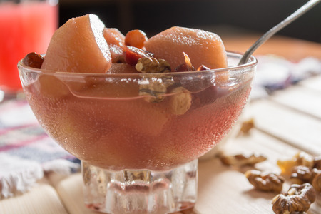 Apple compote with dried fruits in the cup on wooden table with decorative walnutsの写真素材