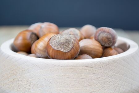 Wooden bowl full of hazzelnuts on the dark background
