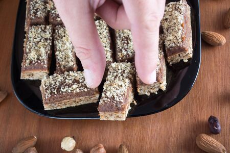Hand picking piece of walnut cake from a plate, shot from aboveの写真素材