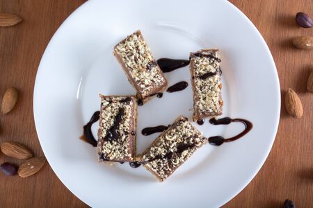 Chocolate cake with walnut cut into squares served on white plateの写真素材