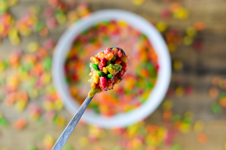 Spoon with colorful rice in the milk with blured background. Selective focus