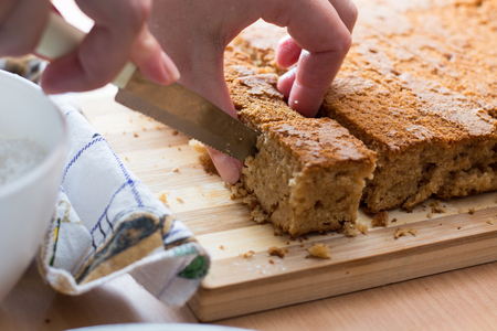Female hands cutting and preparing cake crust on wooden  plateの写真素材