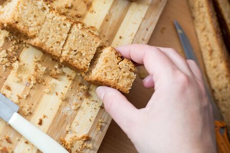 Female hands cutting and preparing cake crust on wooden  plateの写真素材