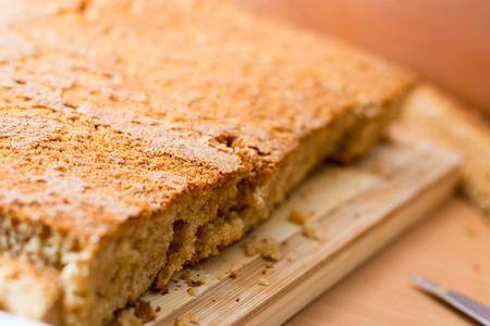 Female hands cutting and preparing cake crust on wooden  plate