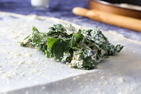Homemade Phyllo or strudel dough with cheese and spinach on a home table cloth ready for cheese burek pie or other kind of traditional pastry.の写真素材