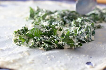 Homemade Phyllo or strudel dough with cheese and spinach on a home table cloth ready for cheese burek pie or other kind of traditional pastry.の写真素材