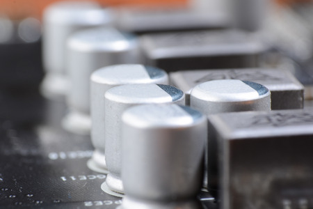 A dusty computer components. Detail of a dusty computer mainboard. Electrolytic capacitor  and conductor visible on the printed circuit board. Selective focusの写真素材