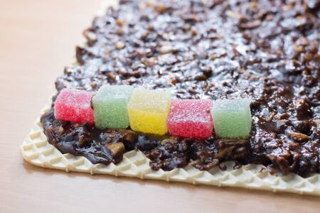Chocolate topping with wallnuts on cake crust for rolled chocolate cake with jelly candiesの写真素材