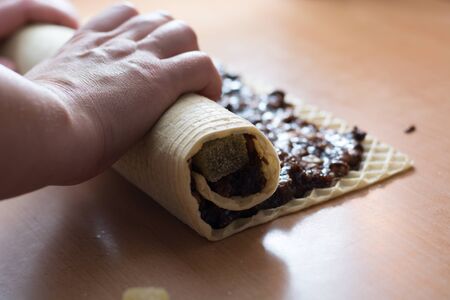 Rolling cake crust with chocolate and jelly candies. Preparing it for cutting with knifeの写真素材
