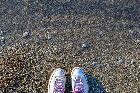 Concept with blue sneakers on bright sea pebbles with space for the text.の写真素材