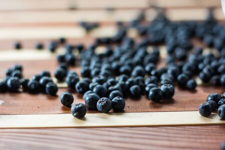 Fresh and tasty aronia spilled on wooden tableの写真素材