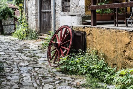 Wooden wheel in the old greek traditional village. Pretty village greek style - artwork in retro style.の写真素材