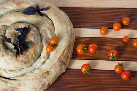 spiral filo pie burek with cherry tomatoes on wooden tableの写真素材
