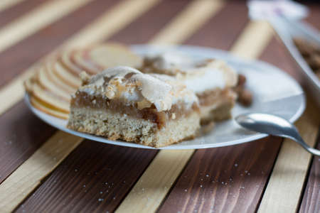Square shape sliced omemade apple pie with kumquats and almonds on wooden background