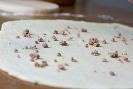 Woman making dough with meat at home on the kitchen tableの写真素材
