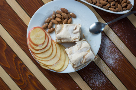 Square shape sliced omemade apple pie with kumquats and almonds on wooden background