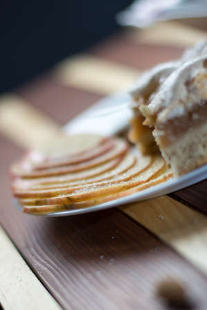 Square shape sliced omemade apple pie with kumquats and almonds on wooden backgroundの写真素材