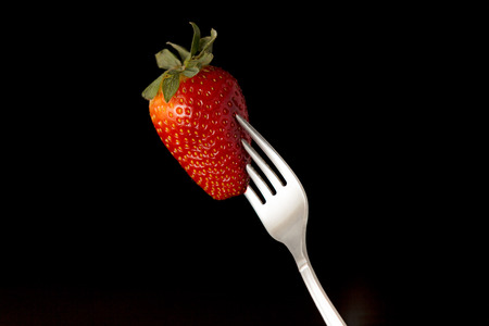 red strawbery and fork in black backgroundの写真素材