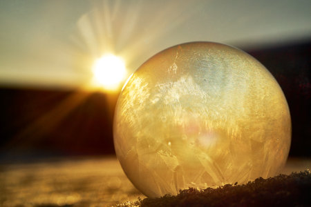 Frozen white soap bubble shot against the sun in the garden