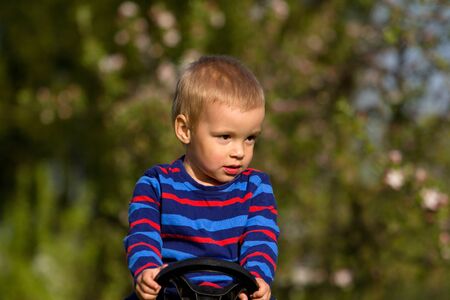 Little boy sits in a baby tractor (portrait).の写真素材