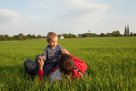 Little boy playing with his father on the grass.の写真素材