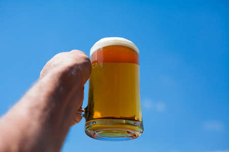 Closeup of a glass of beer contra a blue sky.の写真素材