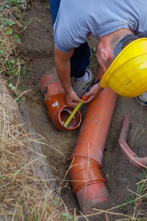 Worker at connecting sewer pipes to measure the diameter of the pipe (Shalow DOF).の写真素材