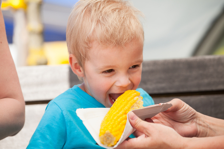 A little boy eating corn on the cob.の写真素材