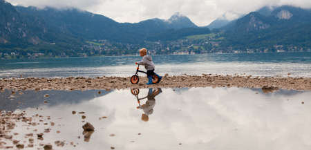 Little boy rides his bike on the lakeshore.の写真素材