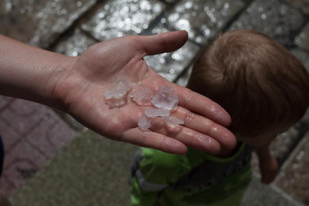 Woman showing the size of the hail hitting the ground as hailの写真素材
