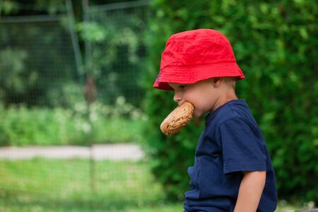 little boy eating outdoors (Shallow DOF).