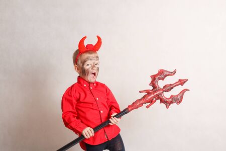 Little boy with trident in a devil costume (on white background).の写真素材