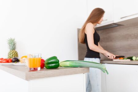 long-haired young woman prepares a modern, stylish kitchen healthy vegetable salad
(Focus on the vegetables in the foreground)の写真素材