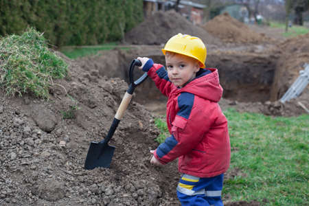 Little boy with a spade helps parents during the construction of the pool.の写真素材