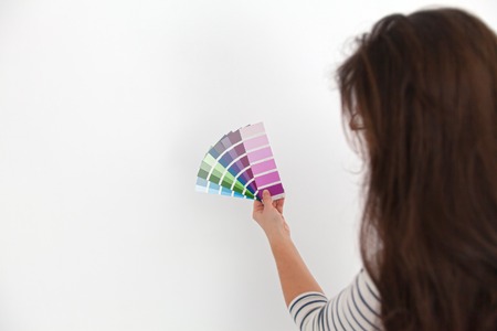 A young woman is looking at a color swatch for painting a room. (Shallow DOF)の写真素材