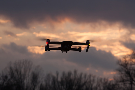 Silhouette of a flying dron at sunset. (Shallow DOF)
