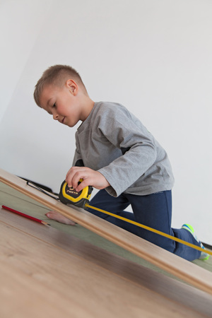 Little boy assists father while laying vinyl floor (Shallow DOF)の写真素材