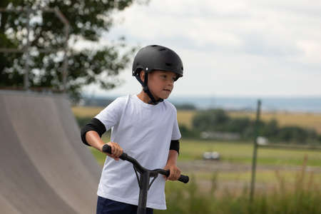 Portrait of a little athlete. A cute little boy rides a scooter in a skatepark. A young novice...