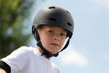 Portrait of a little athlete. A cute little boy rides a scooter in a skatepark. A young novice...