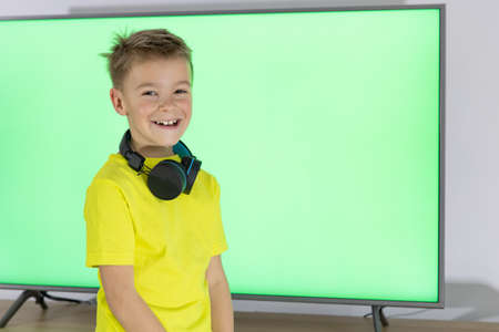 Little boy dancing. Child with headphones dancing and singing in front of television.