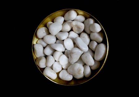 white royal sapphire rock pebbles in golden bowl photographed against a black background. - Imageの写真素材