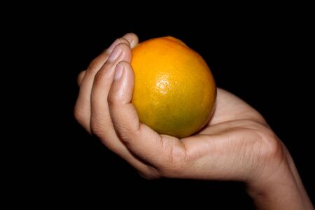 hand holding fresh sliced orange fruit isolated on black backgroundの写真素材