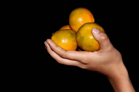 hand holding fresh sliced orange fruit isolated on black backgroundの写真素材
